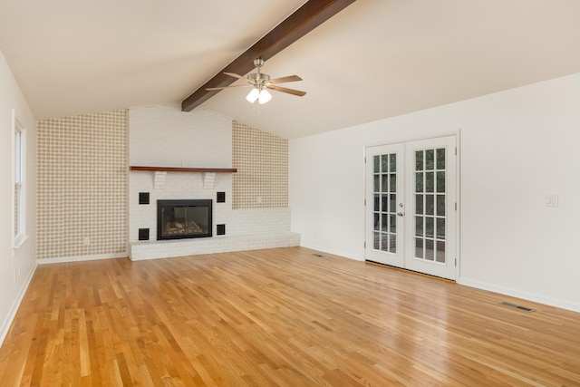 unfurnished living room featuring lofted ceiling with beams, light hardwood / wood-style floors, a fireplace, and ceiling fan