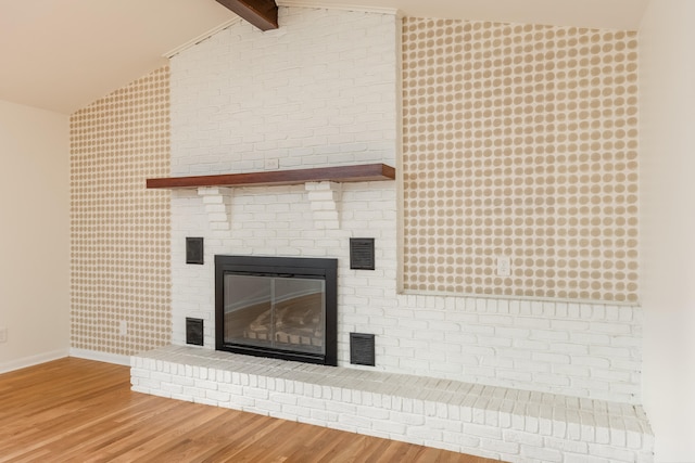 details with wood-type flooring, beamed ceiling, and a fireplace