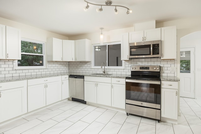 kitchen featuring white cabinets, stainless steel appliances, backsplash, and sink