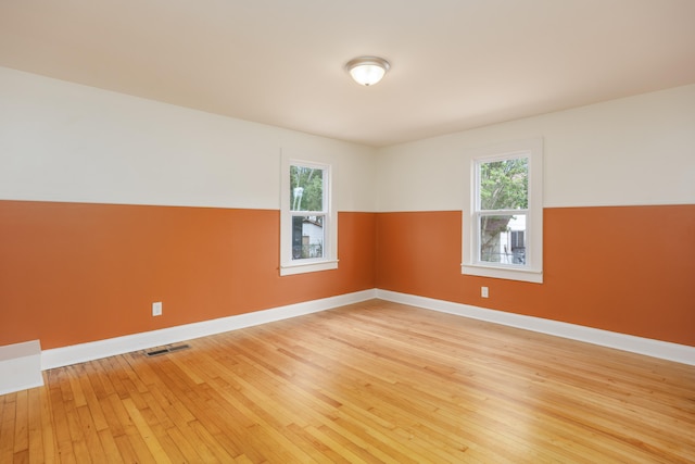 empty room with plenty of natural light and hardwood / wood-style floors