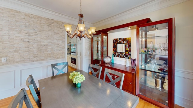 dining area with an inviting chandelier, light wood-type flooring, and crown molding