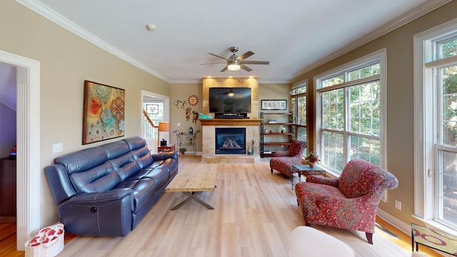 living room with wood-type flooring, ceiling fan, a fireplace, and crown molding