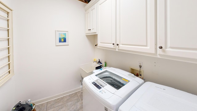 laundry room with cabinets, light tile patterned floors, separate washer and dryer, and sink