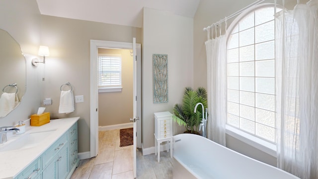 bathroom featuring a tub to relax in, vaulted ceiling, vanity, and tile patterned floors