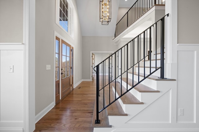 entryway with a towering ceiling, an inviting chandelier, and hardwood / wood-style floors