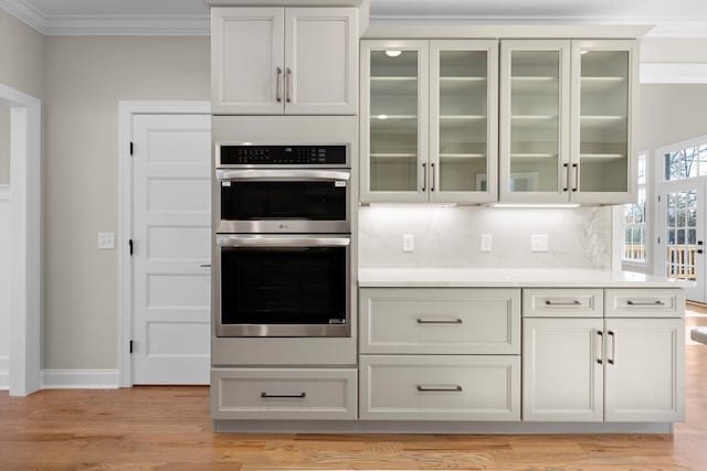 kitchen with white cabinets, stainless steel double oven, tasteful backsplash, and crown molding