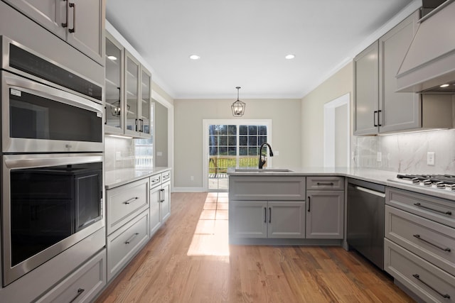 kitchen featuring tasteful backsplash, custom range hood, gray cabinets, appliances with stainless steel finishes, and sink