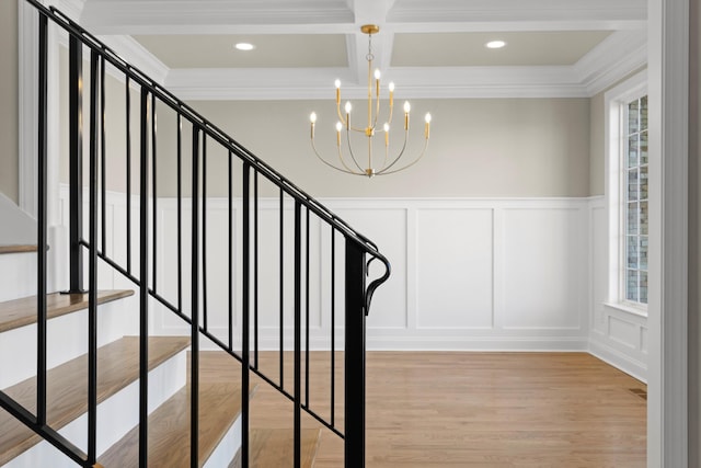 staircase with beamed ceiling, ornamental molding, wood-type flooring, coffered ceiling, and a chandelier