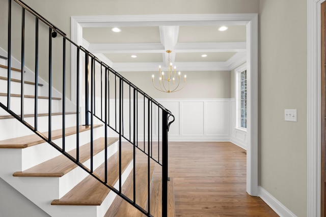 stairs featuring hardwood / wood-style floors, coffered ceiling, crown molding, beam ceiling, and an inviting chandelier