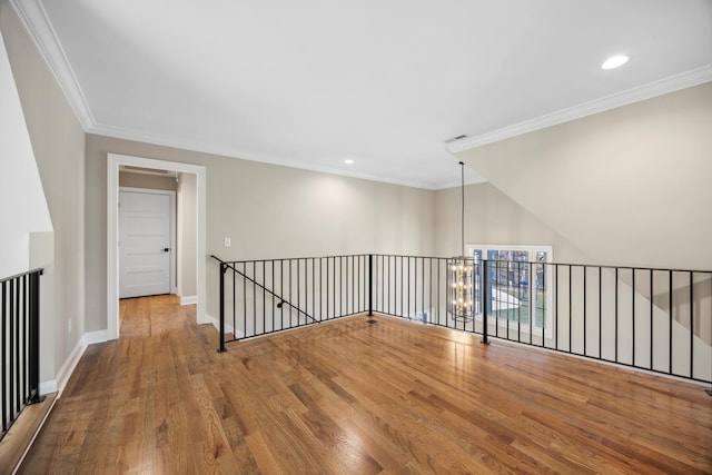 empty room with hardwood / wood-style floors, ornamental molding, and a notable chandelier