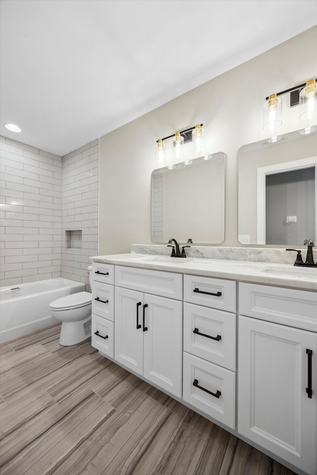 full bathroom with hardwood / wood-style floors, toilet, vanity, and tiled shower / bath