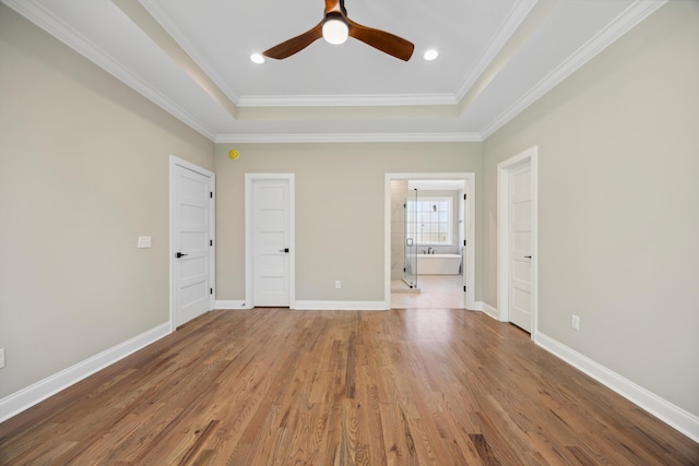 unfurnished bedroom featuring a raised ceiling, ceiling fan, hardwood / wood-style flooring, and crown molding