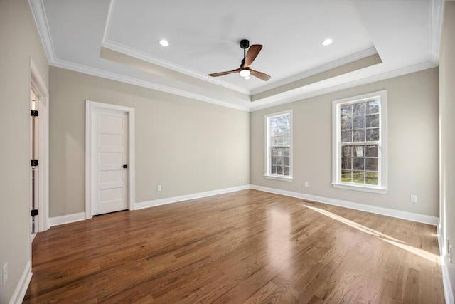 spare room with crown molding, dark hardwood / wood-style floors, and a tray ceiling