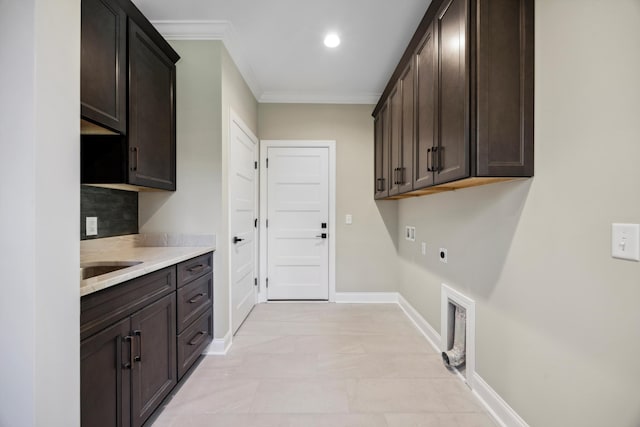 laundry room featuring electric dryer hookup, ornamental molding, and cabinets