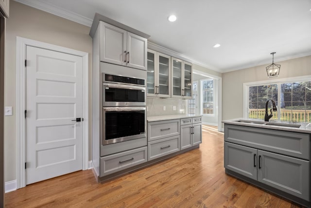 kitchen with pendant lighting, a chandelier, gray cabinetry, double oven, and sink