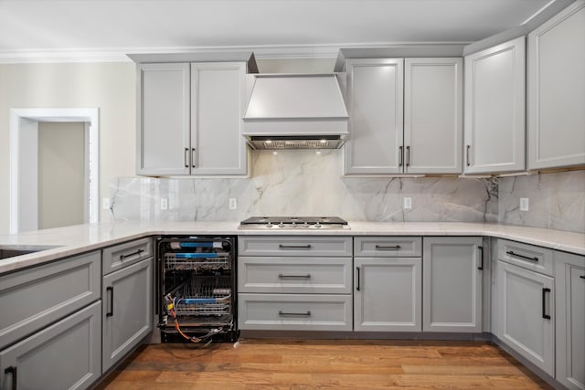 kitchen with custom exhaust hood, gray cabinets, wine cooler, stainless steel gas stovetop, and tasteful backsplash