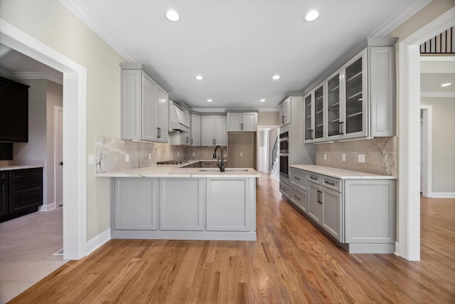 kitchen featuring stainless steel appliances, tasteful backsplash, kitchen peninsula, light hardwood / wood-style flooring, and crown molding