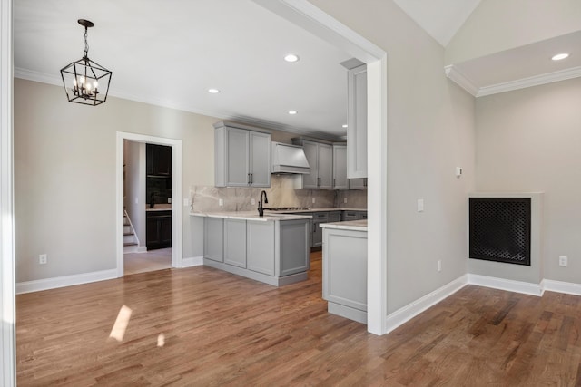 kitchen with vaulted ceiling, gray cabinetry, kitchen peninsula, custom range hood, and backsplash