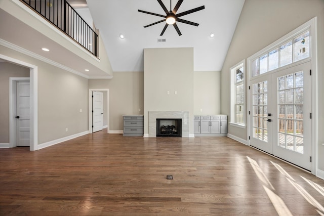 unfurnished living room with dark hardwood / wood-style flooring, french doors, a towering ceiling, and a fireplace