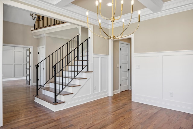 stairs with beam ceiling, a notable chandelier, crown molding, and wood-type flooring