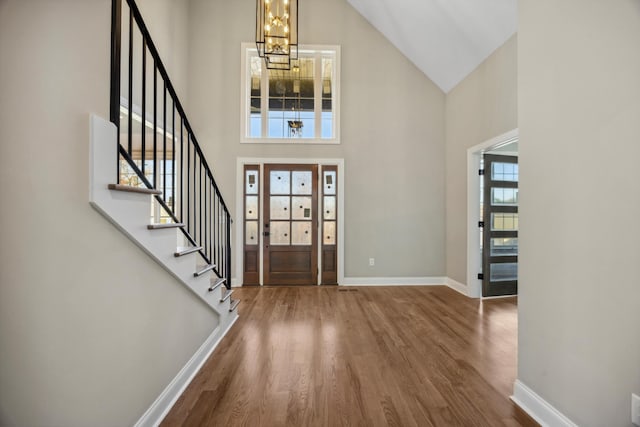 foyer entrance with a high ceiling, a notable chandelier, and hardwood / wood-style flooring