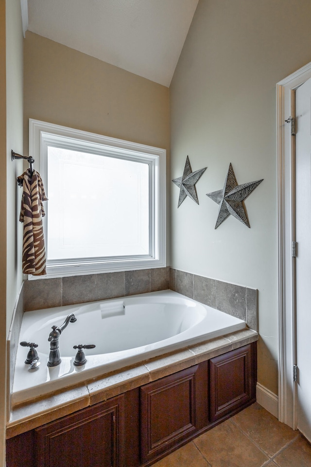 bathroom featuring a tub to relax in, lofted ceiling, and tile patterned floors