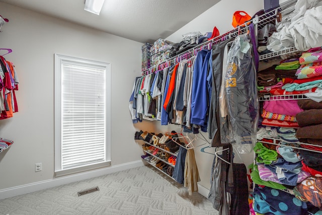 walk in closet featuring light carpet