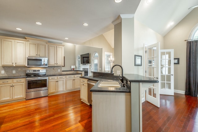 kitchen featuring sink, cream cabinets, hardwood / wood-style flooring, appliances with stainless steel finishes, and decorative backsplash