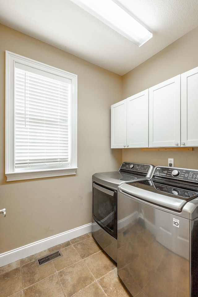 laundry area with cabinets, light tile patterned floors, and washing machine and clothes dryer