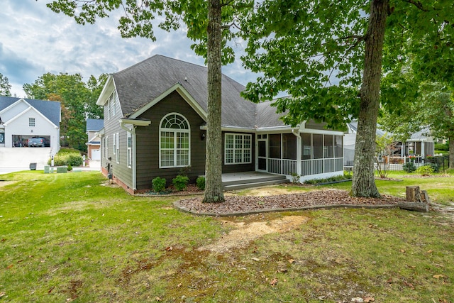 back of house featuring a lawn, a garage, and a sunroom