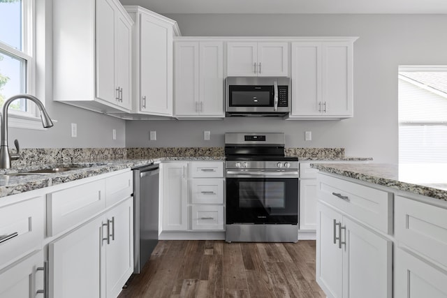 kitchen featuring appliances with stainless steel finishes, white cabinetry, dark hardwood / wood-style floors, and sink