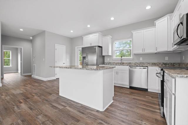 kitchen with white cabinets, a wealth of natural light, appliances with stainless steel finishes, and a kitchen island