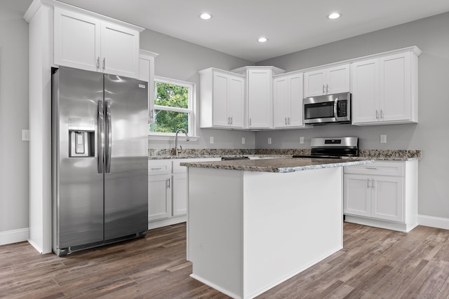 kitchen featuring dark stone counters, dark hardwood / wood-style flooring, stainless steel appliances, and white cabinets