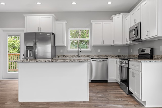 kitchen with appliances with stainless steel finishes, wood-type flooring, plenty of natural light, and white cabinets