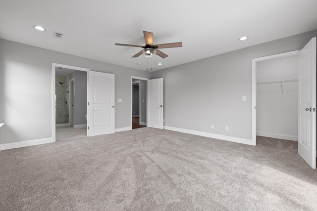 unfurnished bedroom with ceiling fan, a closet, carpet flooring, and a walk in closet