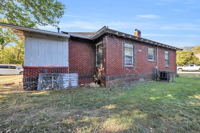 view of side of home with central AC and a yard