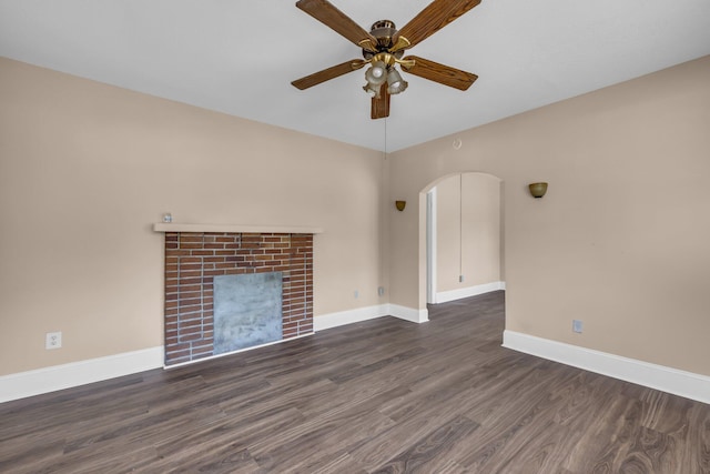 unfurnished living room with a brick fireplace, dark hardwood / wood-style floors, and ceiling fan