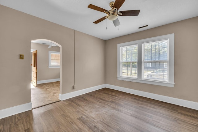 empty room featuring a wealth of natural light, hardwood / wood-style flooring, and ceiling fan