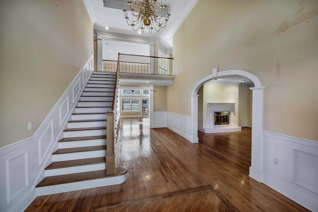 interior space featuring a notable chandelier, a high ceiling, ornamental molding, and hardwood / wood-style flooring