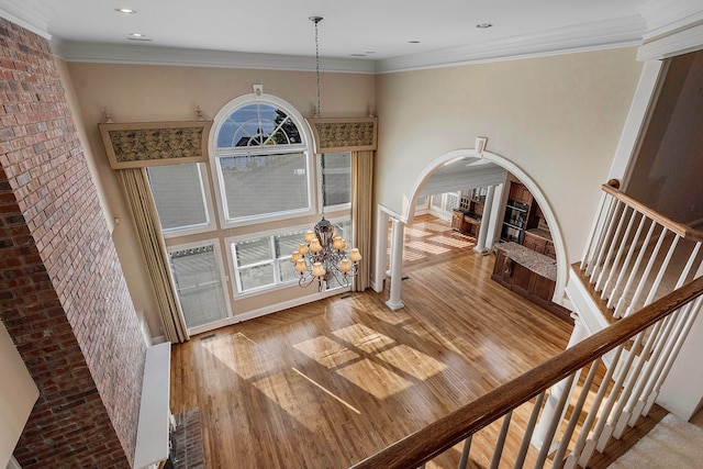 interior space featuring wood-type flooring, a notable chandelier, ornamental molding, and a wealth of natural light