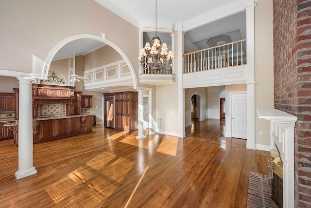 living room featuring hardwood / wood-style floors, decorative columns, and a towering ceiling