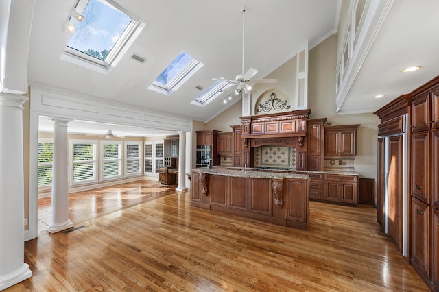 kitchen with light hardwood / wood-style floors, a center island, decorative columns, a skylight, and ceiling fan