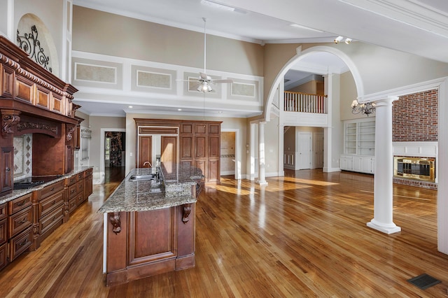 kitchen with a high ceiling, decorative columns, hardwood / wood-style floors, and ceiling fan