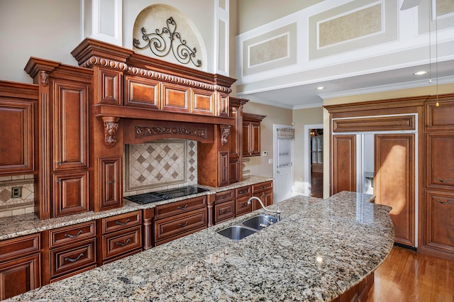 kitchen with light stone counters, light hardwood / wood-style floors, sink, decorative backsplash, and ornamental molding