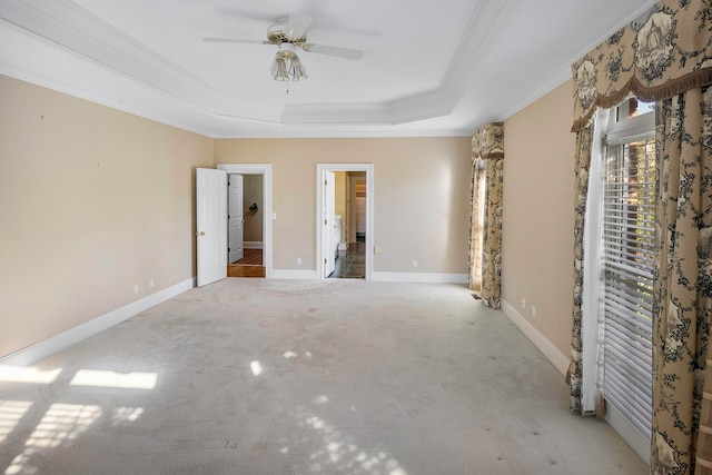 unfurnished bedroom with ornamental molding, a tray ceiling, ceiling fan, and light colored carpet