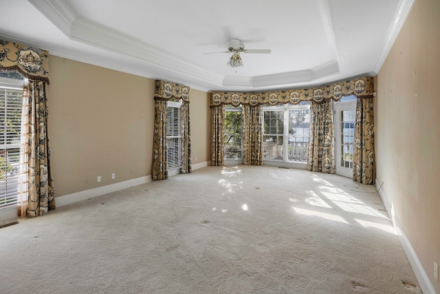 carpeted empty room with a raised ceiling, crown molding, and ceiling fan