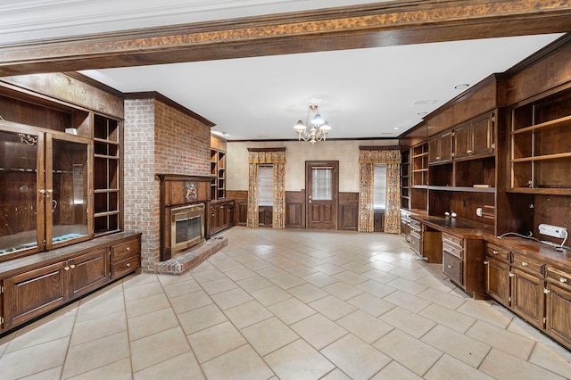 tiled living room featuring an inviting chandelier, a fireplace, crown molding, and built in features