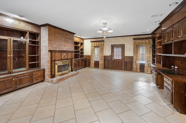 unfurnished living room with a notable chandelier, built in shelves, a fireplace, light tile patterned floors, and ornamental molding