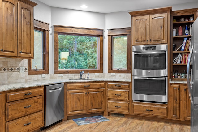 kitchen featuring light hardwood / wood-style floors, tasteful backsplash, sink, stainless steel appliances, and light stone countertops