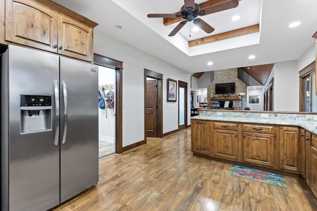 kitchen featuring light stone counters, stainless steel fridge with ice dispenser, a raised ceiling, hardwood / wood-style floors, and ceiling fan